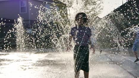 little girl jumps and plays in a water fountain in slow motion