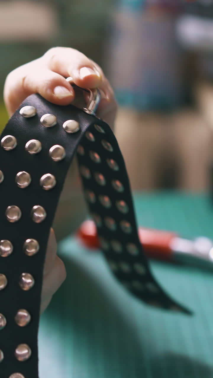 CU: Professional woman designer screws stylish silver accessory into black leather choker on cutting mat close view