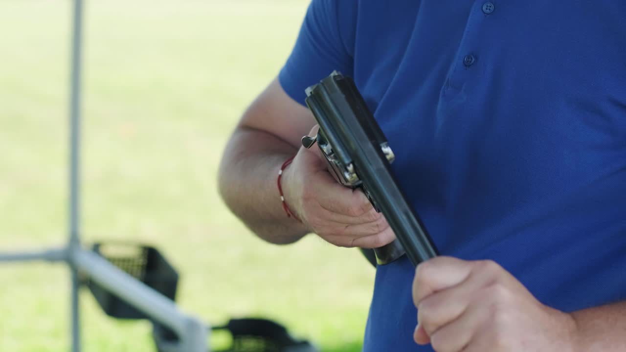 스포츠맨이 이중 배럴 건으로 총을 고, 슈팅 테스트를 위한 스포츠 경기장은 날아다니는 스케이트를 고 있습니다.