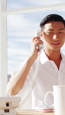 a man calling and typing on computer