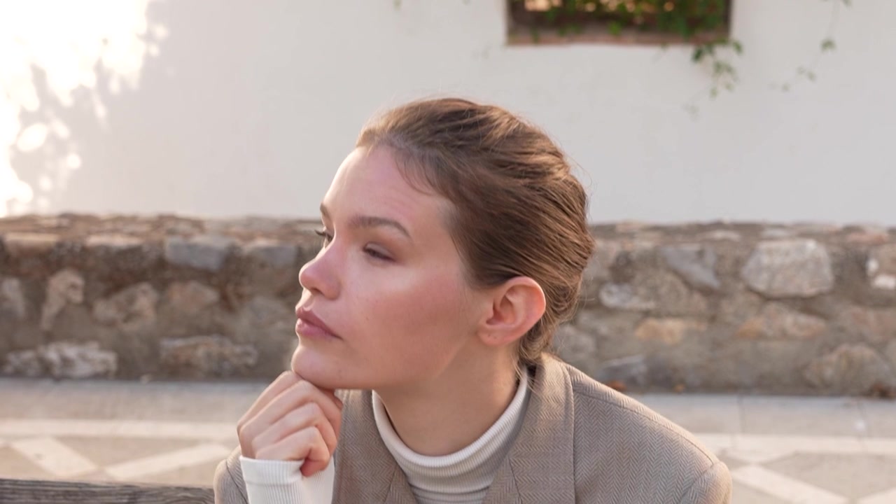 Una giovane donna sicura di sé posa con grazia alla luce naturale del sole, mettendo in mostra la sua eleganza.