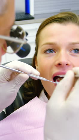 dentista examinando a una paciente femenina con herramientas