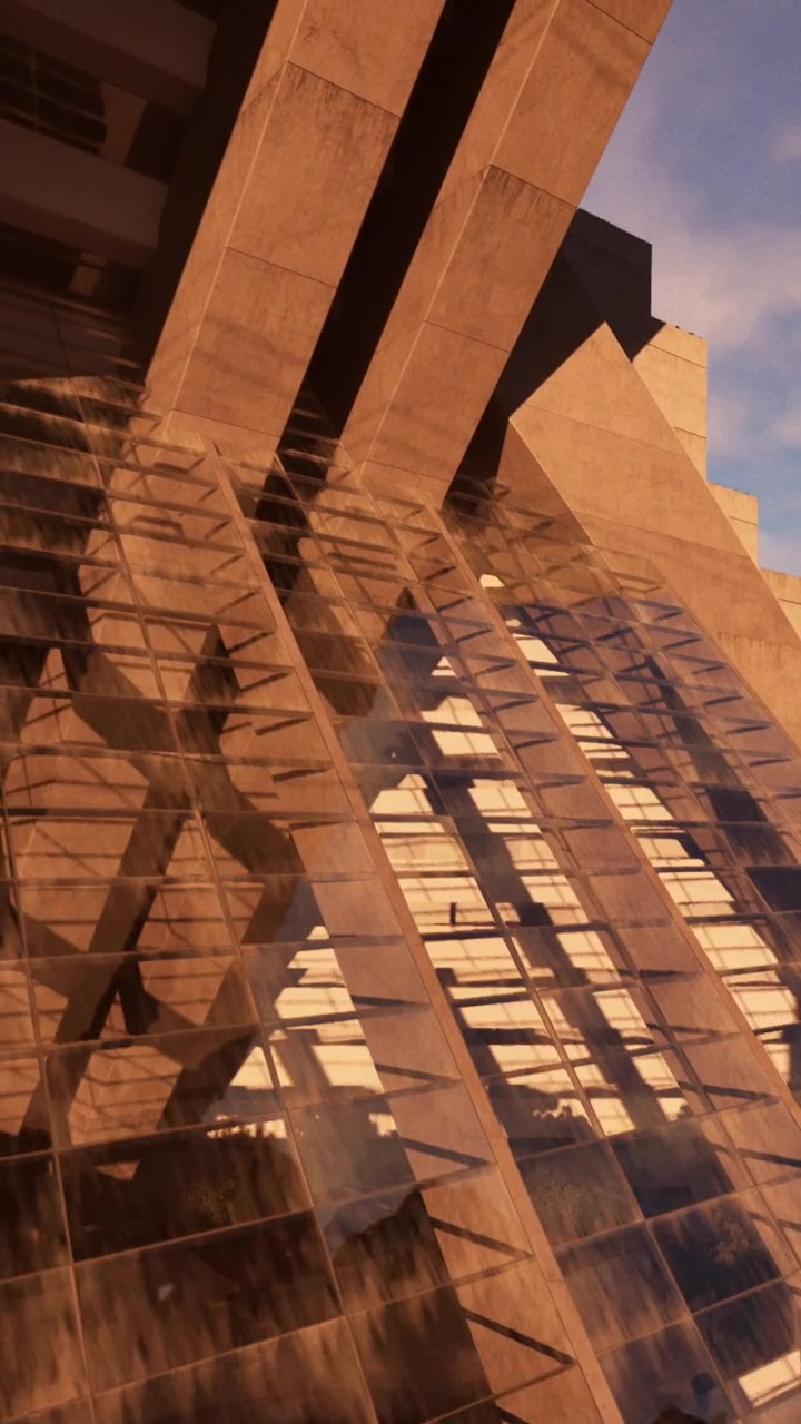 Edifício moderno apresenta grande fachada de vidro e formas geométricas ao pôr do sol