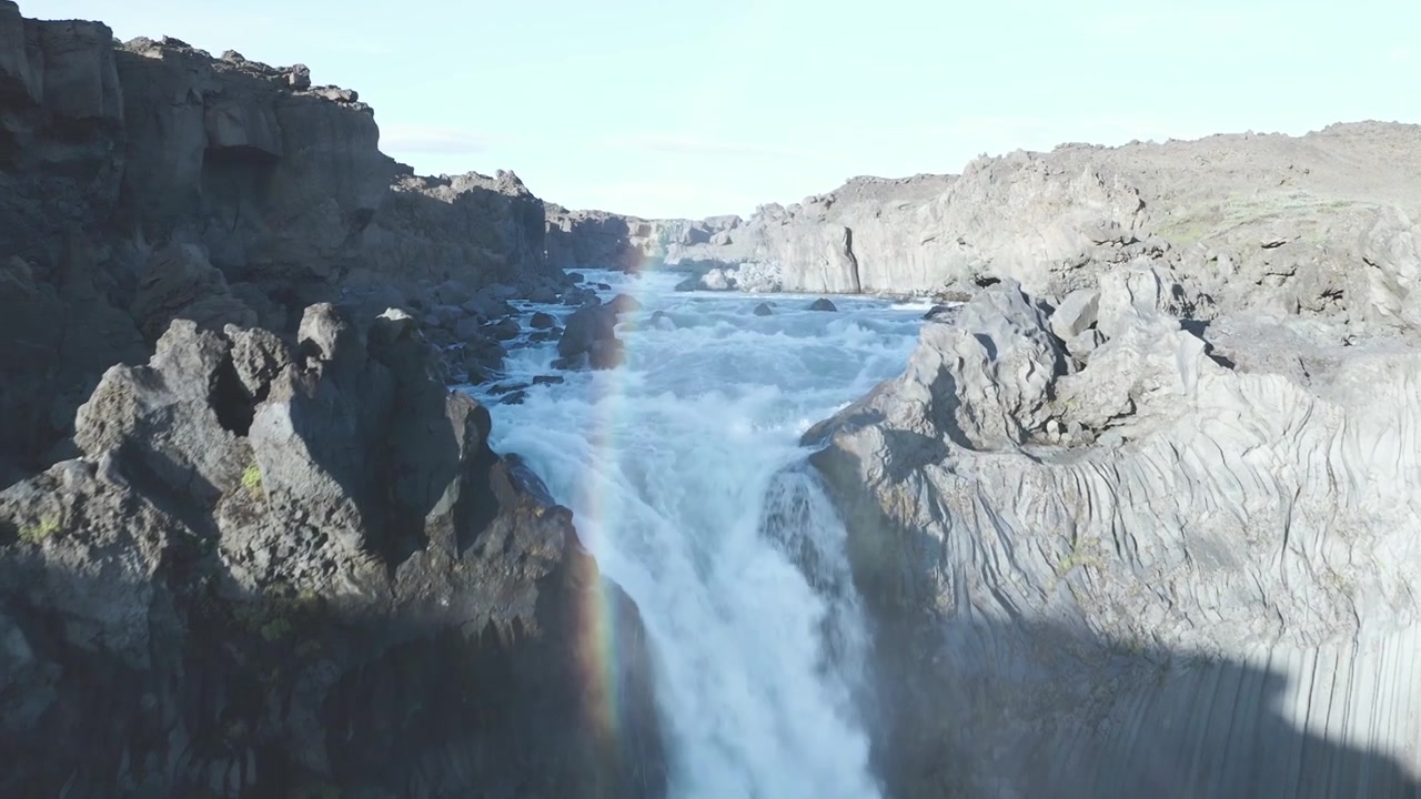 Volo in un canyon, fino a una cascata con un arcobaleno visibile negli altipiani islandesi.