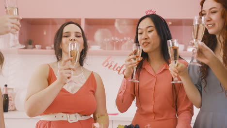 group of friends and bachelor girl around a table with food toasting with champagne crystal glasses