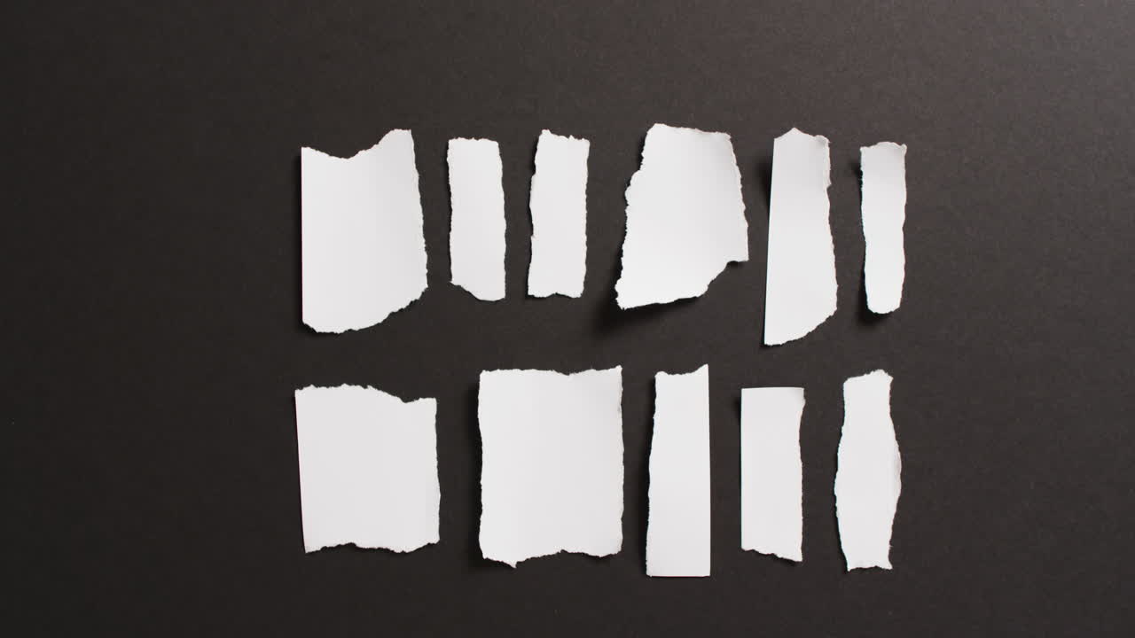 video de primer plano de varias piezas rasgadas de papel blanco sobre fondo negro