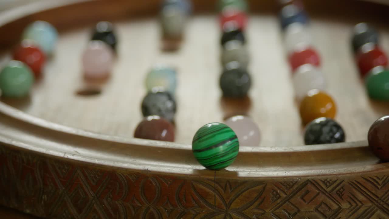 Close-up médio de um homem jogando um jogo de paciência de madeira ornamentada. Clipe 5