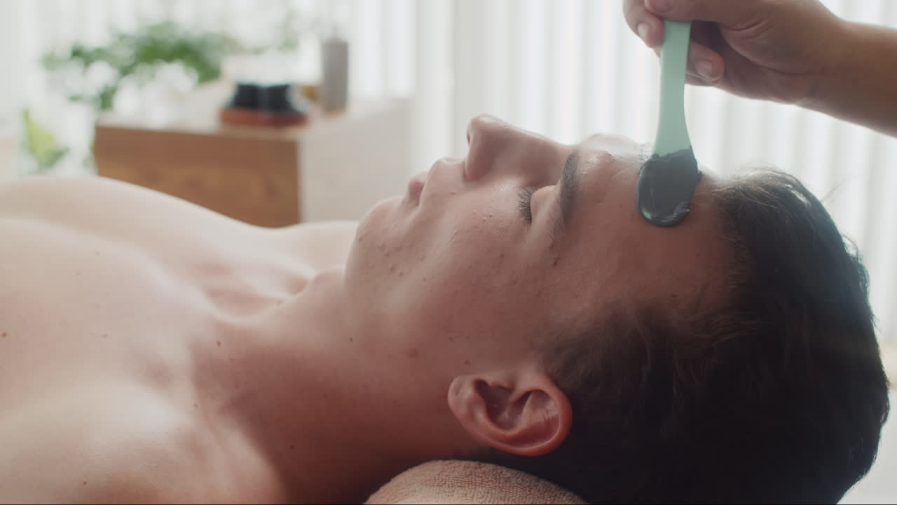Cosmetologist Applying Clay Mask on Face of Man