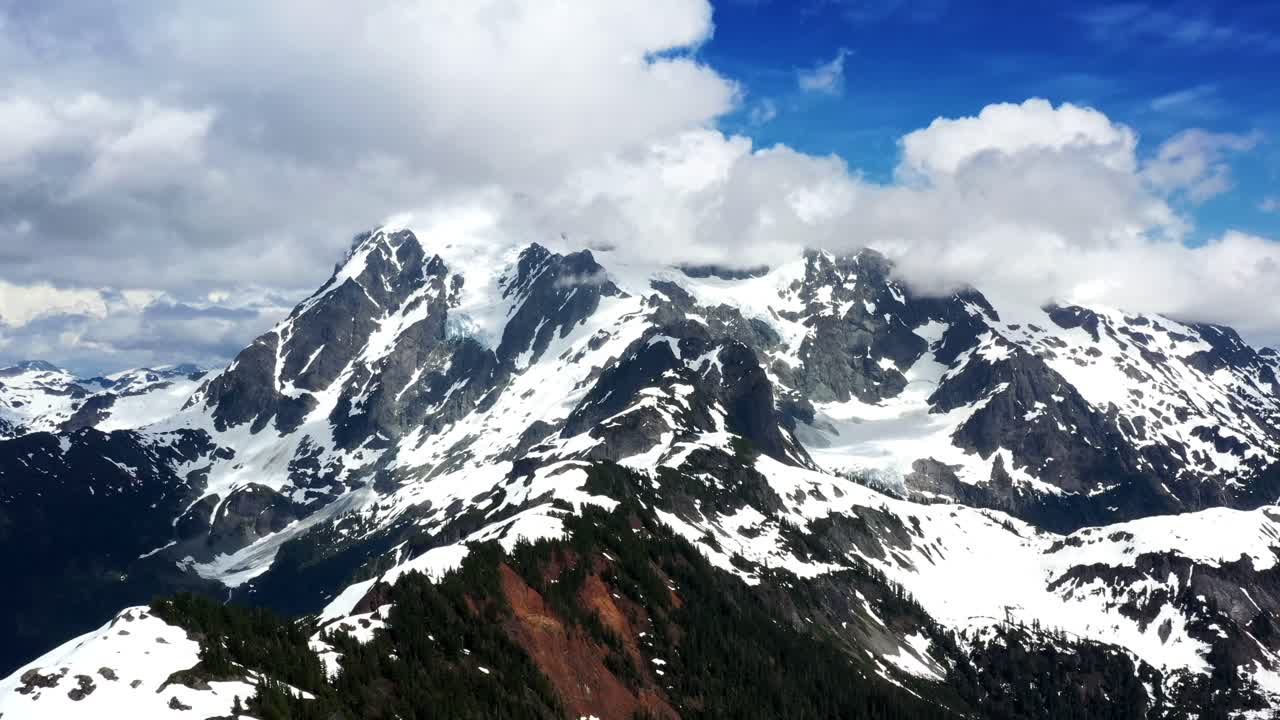 Gorgeous aerial view of a mountain range covered in snow on a cloudy blue sky day in the Pacific Northwest, Washington State.