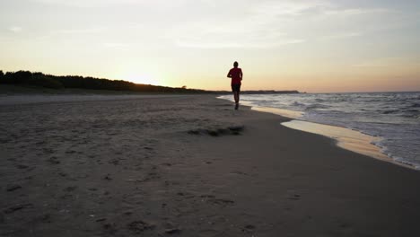 slow motion of a man running on the beach at sunset in swinoujscie, poland