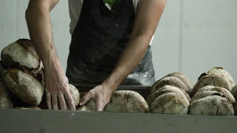 baker arranging freshly baked bread in neat piles - medium shot