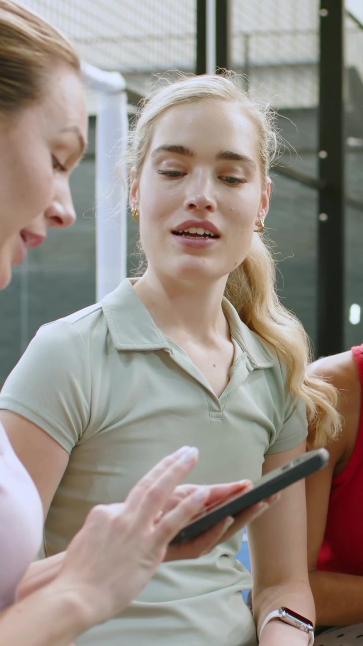 Vertikal video: Reagerende kvinde i midten med limefarvet top læner sig op ad bænken, mens hun scroller på telefonen til venstre og tjekker sit ur.