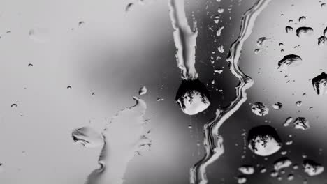 macro water drops flowing on a window glass.the landscape is reflected in the drops.