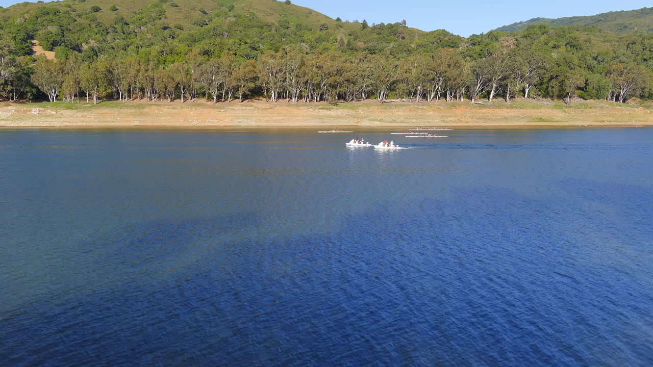 carrera de equipos de remo en la superficie del lago en el embalse de lexington en california en un día soleado