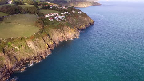 aerial shot flying along the devon coast in the uk, showing distant houses