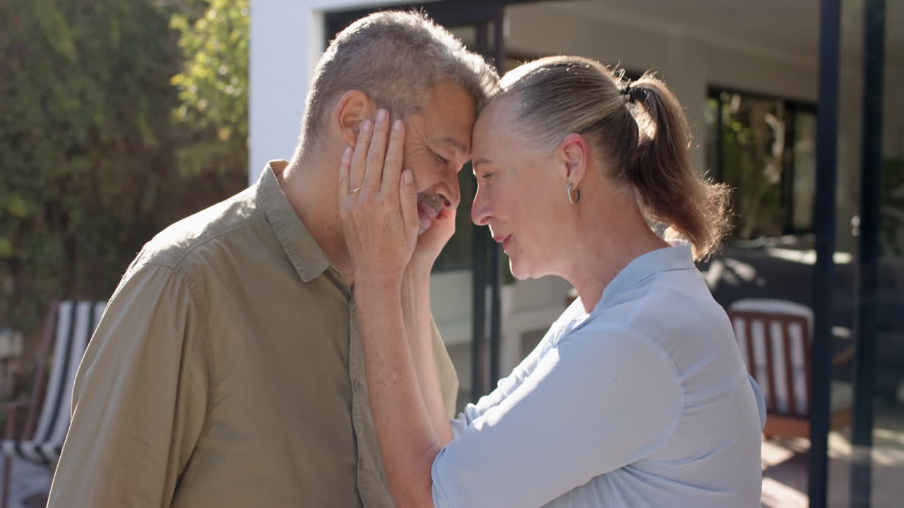 Touching man's face, senior woman sharing tender moment outdoors