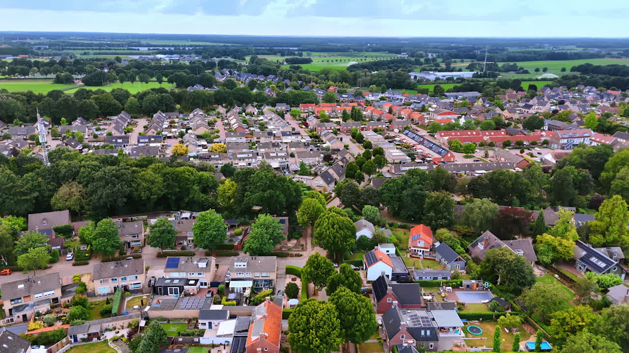 Cozy residential area with multiple low-rise houses. Scenery of the town with lush greenery in the Netherlands. Aerial view