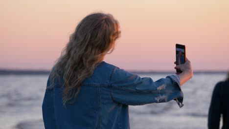Shot-from-side-how-young-beautiful-woman-takes-a-selfie-near-the-sea