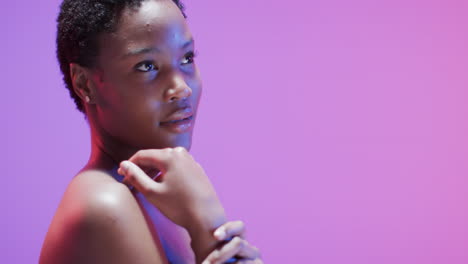 african american woman with short dark hair in blue and pink light with copy space, slow motion