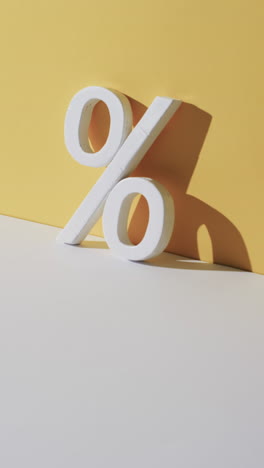 vertical video of white percent sign with copy space against yellow background