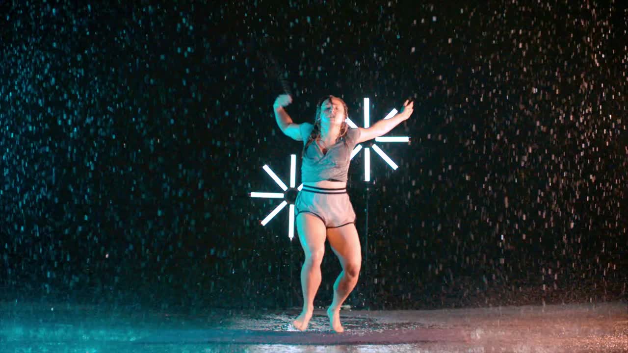 Caucasian young female dancer performing contemporary dance moves, indoor rain
