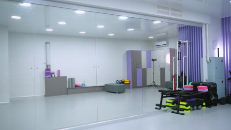 de moderne sportschool blijft grotendeels donker, verlicht door een paar lichtbronnen die een zachte gloed geven. fitnessapparatuur, waaronder workoutmachines en een muziekdoos, is zwak zichtbaar op de achtergrond.