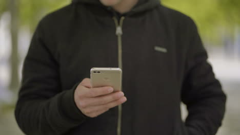 Captura-Recortada-De-Un-Hombre-Usando-Un-Teléfono-Inteligente-Al-Aire-Libre