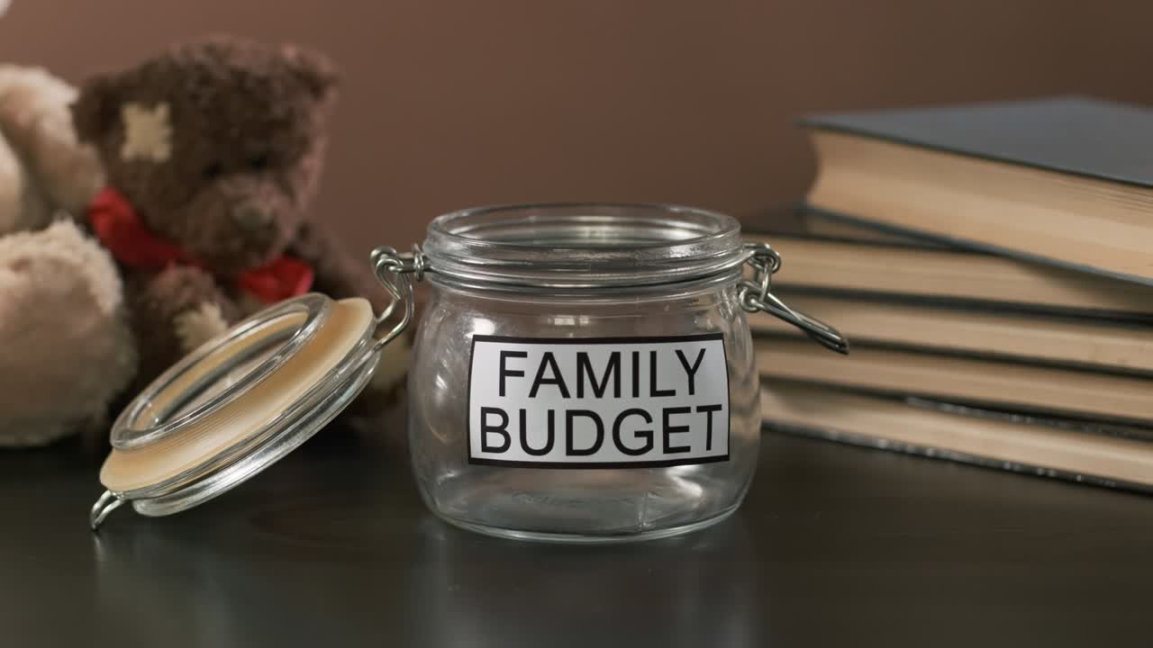 Male Puts Banknote into Glass with Family Savings
