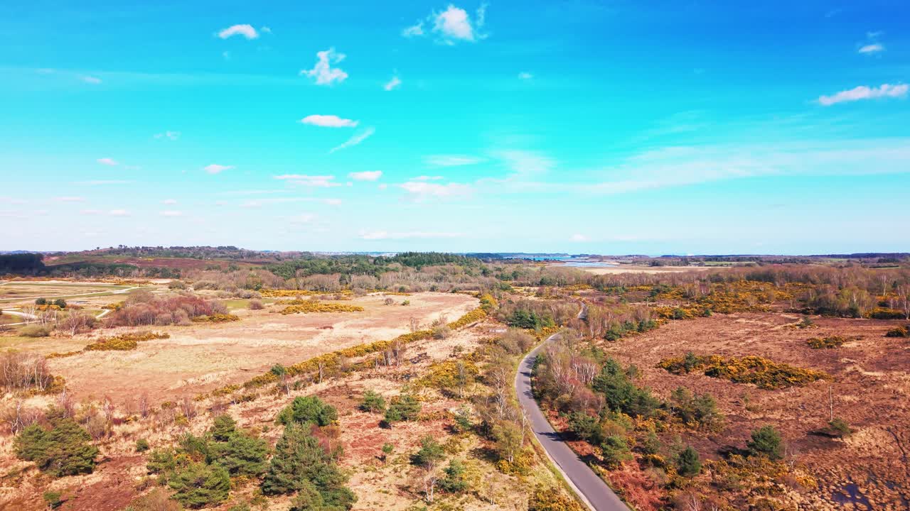Flyfoto av heiområde og landskap med svingete vei gjennom et naturlig landskap under klar blå himmel i Storbritannia.