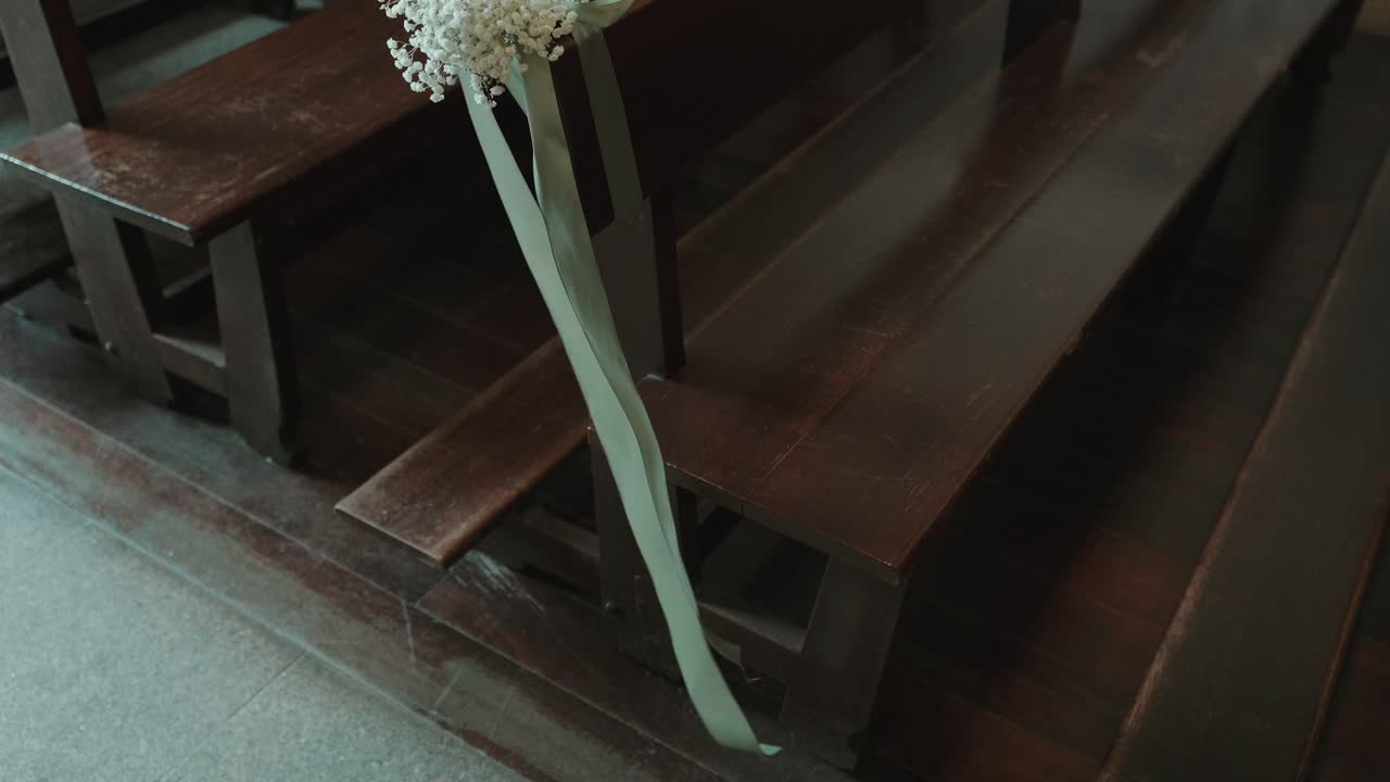 wooden church pew decorated with white flowers and ribbon