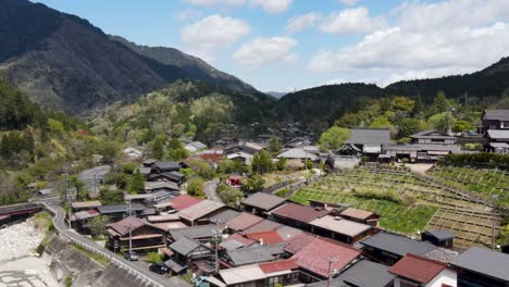 aerial view over rooftops of tsumago-juku town in nagano prefecture. dolly back with valley view in the background