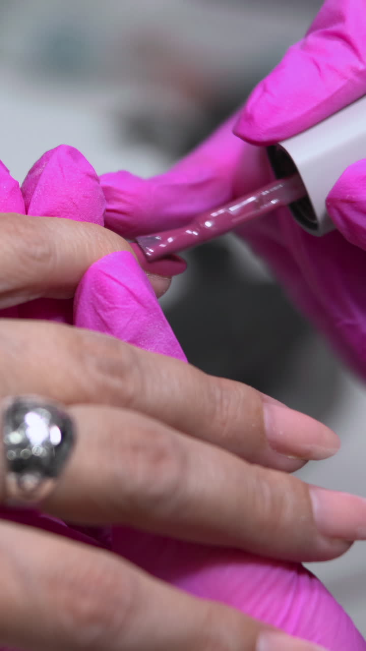 CloseUp Manicurist Applying Clear Basecoat On Nails With Pink Gloves And Silver Ring, Steady Brush Strokes. Media