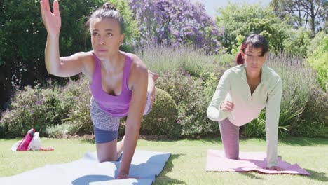 happy biracial sisters doing yoga and stretching in garden, in slow motion