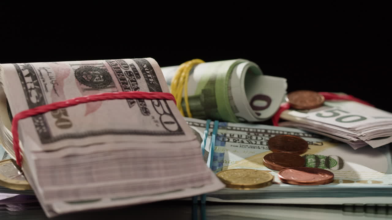 Pile di banconote di euro e dollari che ruotano su sfondo scuro