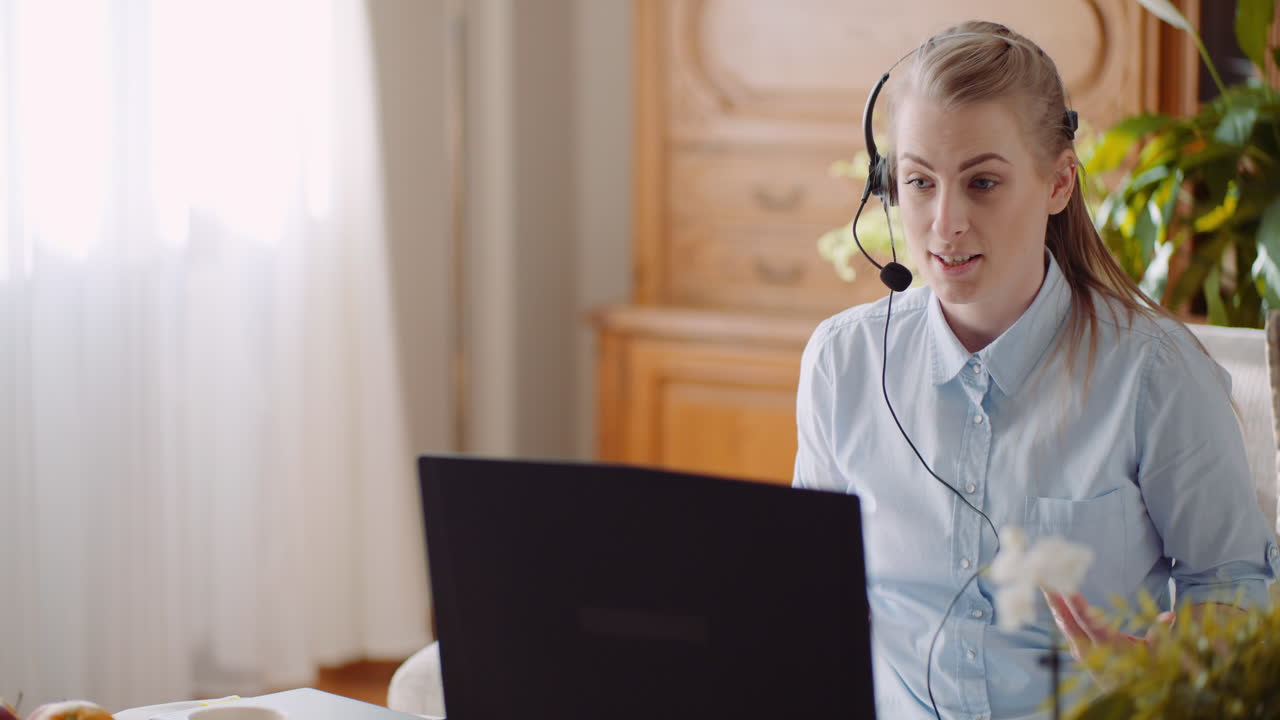 Sælger med headset taler med kunde og holder videomøde på bærbar computer 1