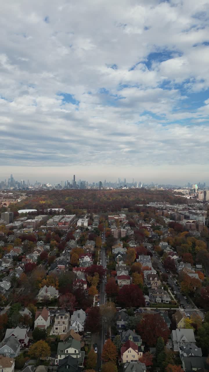 High aerial angle of Brooklyn in autumn showing blocks of row homes, sidewalks, and trees in peak foliage. Bright colors highlight urban symmetry and seasonal change