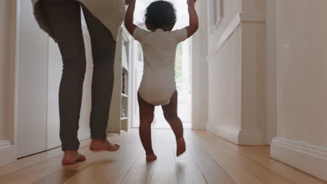 baby learning to walk toddler taking first steps with mother helping infant teaching child at home