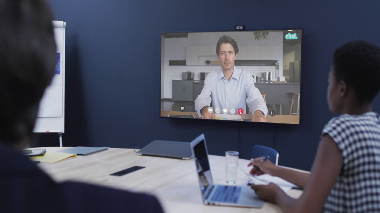 diversas personas de negocios en videollamada con un colega caucásico en la pantalla de televisión
