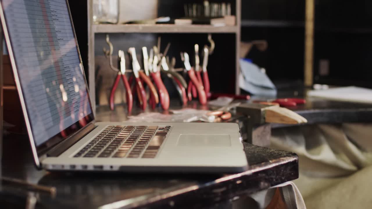 Close up of laptop and handcraft tools in studio in slow motion