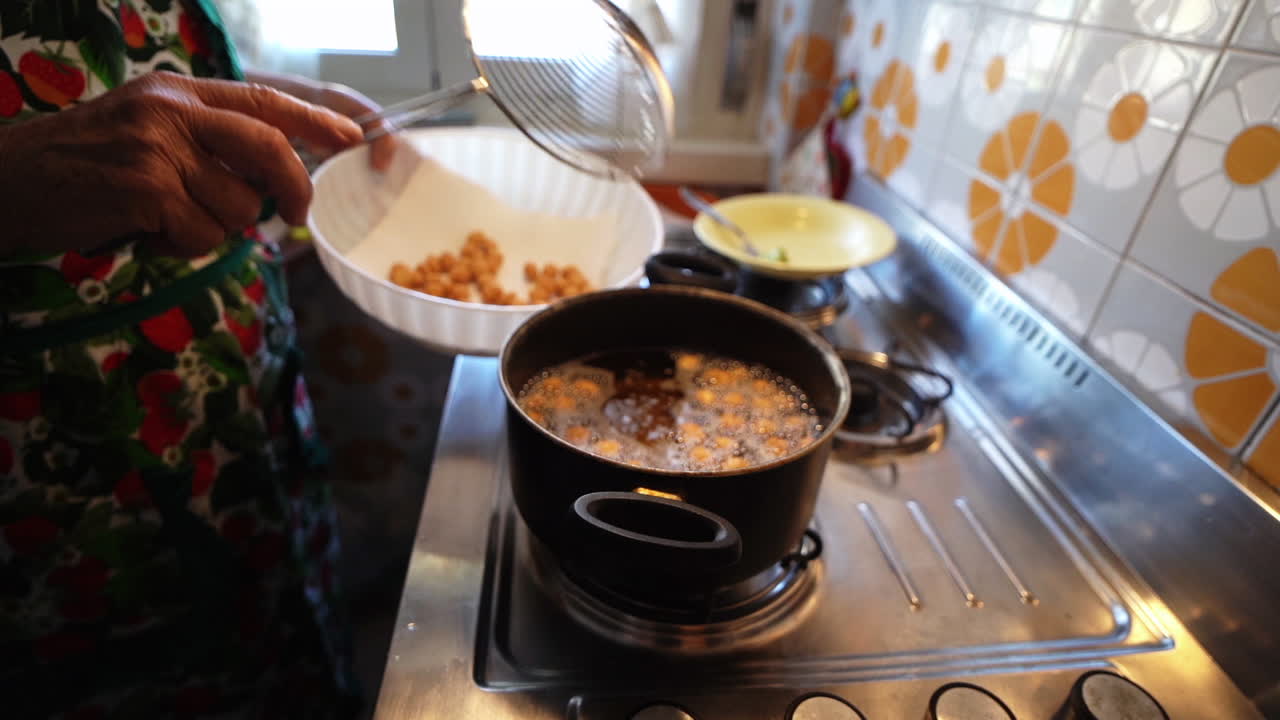 튀긴 struffoli 패스트리에서 끓는 기름을 제거하여 그릇에 담습니다.