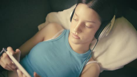 teen girl relaxing at home, listening to music with headphones and using her smartphone. a calm, intimate moment of digital leisure in a cozy setting.