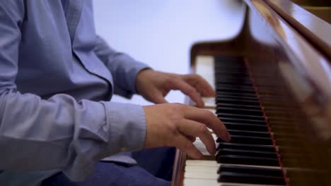 elegante hombre de mediana edad tocando música clásica en un piano en un restaurante con un cinemático de fondo borroso