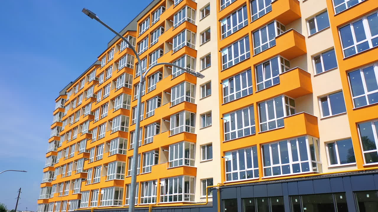 New apartment building. Exterior of a multi-storey house of modern design in the city. Facade of bright urban building with large windows.
