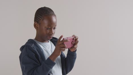 retrato de estudio de niño emocionado en juegos de espectro asd en teléfono móvil contra fondo blanco