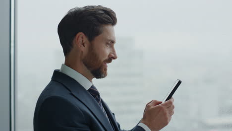 office manager typing smartphone standing near skyscraper window close up.