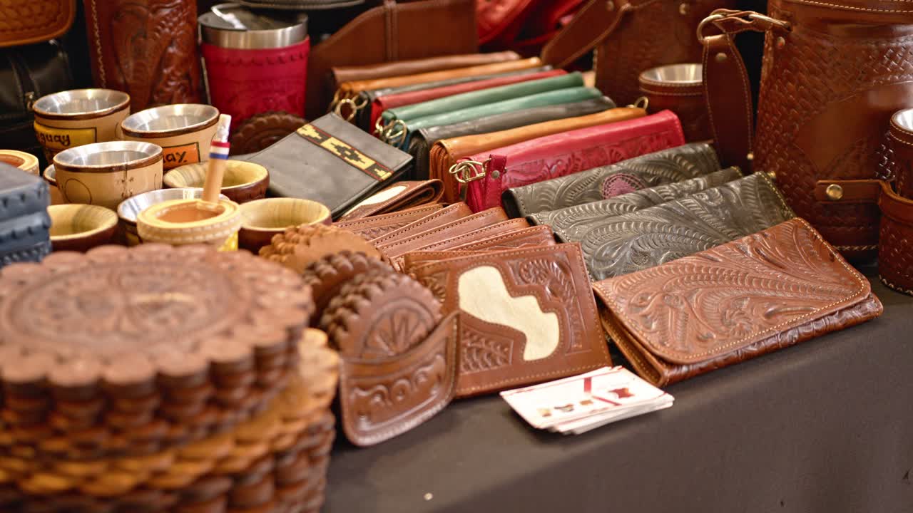 Exhibition of genuine leather items in Paraguay, handcrafted with brown and red leather, including wrapped thermoses. The leather is carved with patterns and figures. Items for gifts and keepsakes