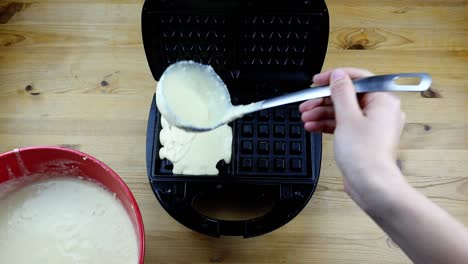 putting waffle dough into a waffle iron