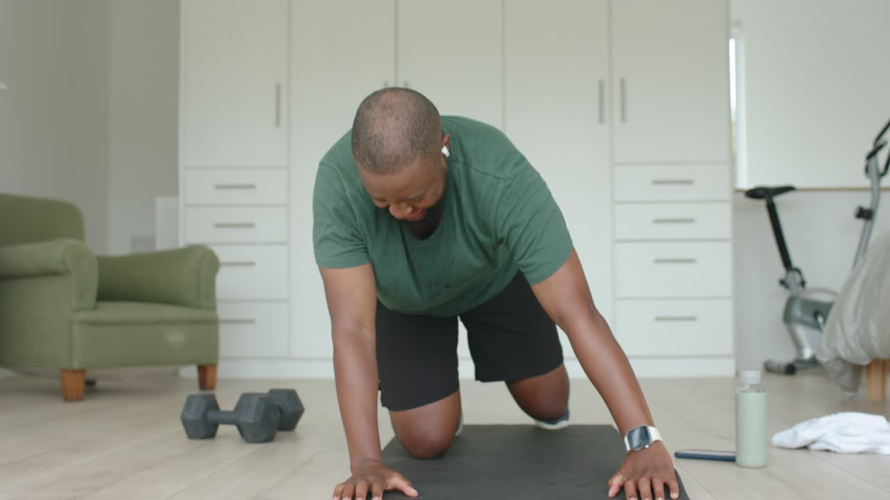 Adult male starting camera recording, performing push-ups on black mat at-home, building strength