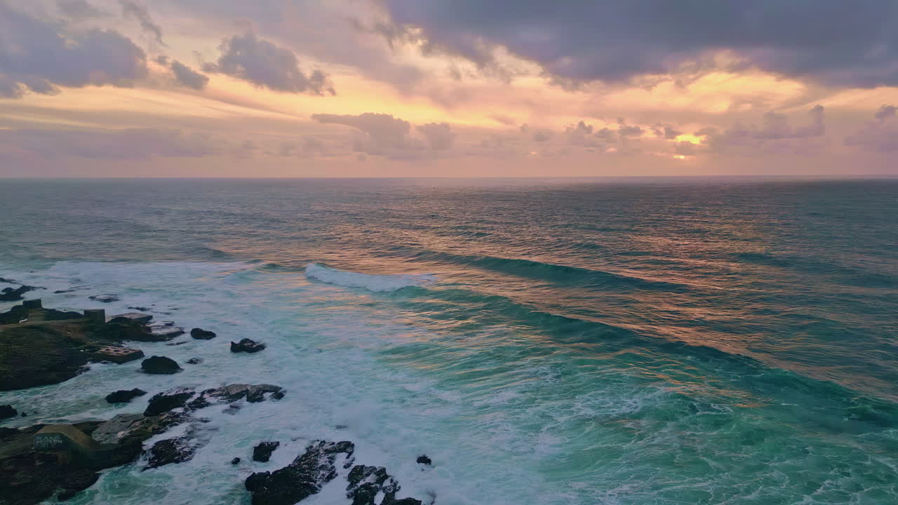 Ocean surface reflecting golden evening light drone view. Sea waves crashing