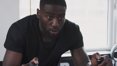 young man training on exercise bike in gym